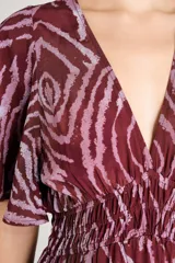 Vestido largo con estampado animal print abstracto en tonos bordó y rosado, escote en V pronunciado, mangas cortas amplias y cintura fruncida elastizada.