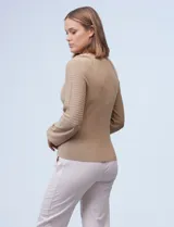 Buzo color beige de tejido combinado con mangas largas caladas y cuello redondo.