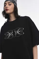 Remera blanca de corte boxy, cuello redondo a la base y mangas cortas. Presenta un pequeño estampado localizado en el centro del pecho que simula un ají en tono rojizo.