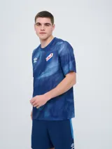 Remera de entrenamiento Umbro del Club Nacional de Football, modelo Press, para hombre. Diseño en tonos de rojo con patrón estampado tipo humo o abstracto, cuello redondo y mangas cortas. Incluye el logo de Umbro y el escudo del club en el pecho.