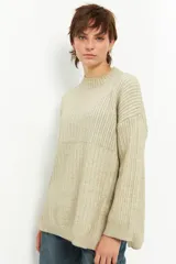 Polera beige de tejido de punto acanalado, corte oversized, cuello alto y aberturas laterales.