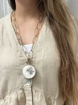 Collar de cadena de eslabones largos en bronce con un dije circular grande que combina bronce y una pieza de guampa natural engarzada.