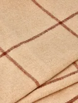 Bufanda de tejido suave y ligero, color beige con diseño de cuadros en marrón. Presenta flecos en los extremos.