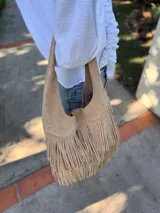 Cartera tipo hobo de cuero color beige con flecos en dos niveles.