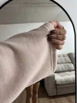 Polerón de cuello alto en color rosa suave, con diseño de calce holgado y mangas amplias. Presenta una textura acanalada fina y un corte relajado que aporta movimiento.