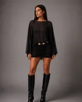 Vestido corto negro con diseño de dos piezas simulado, compuesto por una blusa de tul transparente con mangas amplias y una falda ajustada con frunces frontales.