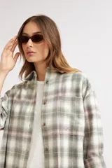 Sobrecamisa oversize de diseño a cuadros en tonos verde, blanco y lila, de manga larga, con bolsillos en el pecho y cierre frontal de botones.