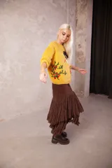 Falda larga de cuero marrón con diseño de capas y flecos largos de lana negra en la parte inferior.