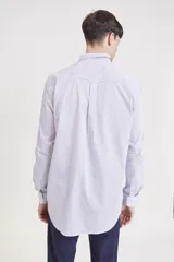 Camisa de manga larga, color rosa claro con finas rayas verticales blancas, cuello camisero y un bolsillo en el pecho.