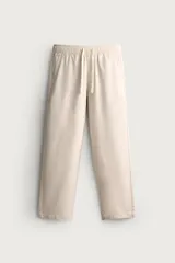 Pantalón de corte regular fit confeccionado en tejido mezcla de algodón, color beige. Presenta cintura elástica con cordón ajustable, bolsillos laterales y bolsillos traseros de vivo.