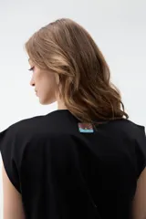 Remera negra sin mangas, de corte holgado, con hombreras marcadas y cuello redondo.