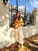 Sweater de punto con diseño geométrico en tonos mostaza, marrón y beige.