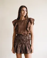 Falda corta de lino color marrón, con diseño fruncido en la cintura y el cuerpo, y un amplio volado en el ruedo.