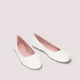 Bailarinas de charol blanco con lazo ajustable en la puntera, suela de goma antideslizante, plantilla de piel con memory foam y forro de tela.