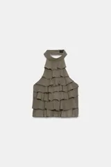 Top de cuello halter color blanco, con múltiples volantes en cascada en todo el frente y la espalda descubierta con cierre de botones y lazada en el cuello.