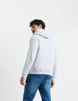 Sweater deportivo con capucha, bolsillo canguro frontal y cordones de ajuste. Presenta un diseño de color azul oscuro con interior de capucha en color verde.