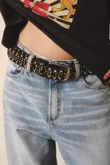 Cinturón de cuero negro con tachas plateadas y doradas, y hebilla metálica plateada.