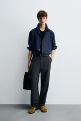 Pantalón de vestir negro, corte recto y relajado, con cintura elástica, cierre frontal con cremallera y botón, bolsillos delanteros y bolsillos traseros de plastrón.