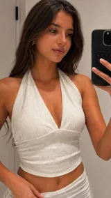 Top de cuello halter con escote en V profundo, confeccionado en tejido texturizado con sutil brillo. Presenta un diseño ajustado con frunces laterales que realzan la silueta.