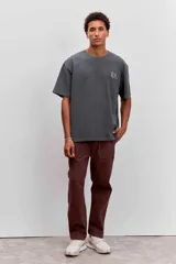 Pantalon de corte recto en color marron, confeccionado en tela resistente, con bolsillos laterales tipo parche y cierre frontal.