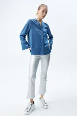 Camisa azul de satén con botones forrados, cuello mao y mangas largas acampanadas.