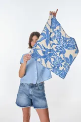 Pañuelo cuadrado de tela color crema con estampado de flores azules.