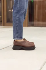 Suecos marrones de cuero con costuras decorativas y suela track negra.