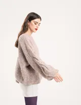 Buzo tejido a mano con lana, color rosa con motas de colores. Diseño oversized, largo entre la cintura y la cadera, con detalle de trenzas en las mangas.