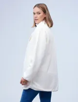 Cárdigan largo reversible color blanco. Un lado es de sherpa y el otro capitoneado. Tiene bolsillos delanteros.