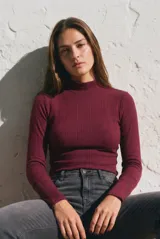Polera de cuello alto y manga larga, confeccionada en tejido de punto acanalado con un ajuste al cuerpo.
