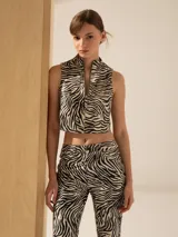 Top corto de cuero ovino con estampado de cebra, cuello alto y cierre metálico frontal.