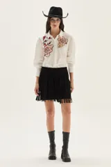 Camisa blanca de algodón con bordados florales en tonos rosados y rojizos en el frente. Presenta mangas largas abullonadas y puños con bordado.