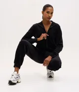 Campera deportiva de plush color negro, con cuello alto, cierre frontal con cremallera y puños ajustados.