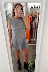 Vestido tejido de punto sin mangas, corte recto y holgado, con cuello redondo. El tejido es jaspeado en tonos grises, azules y amarillos claros, con brillo sutil de lurex.