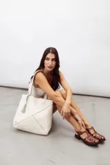 Bolso tipo shopper color rojo, confeccionado en 100% cuero vacuno, con diseño geométrico de paneles y detalle de fleco decorativo colgante.