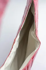 Cartera acolchada negra de silueta ovalada con asa circular integrada y diseño matelassé en rombos.