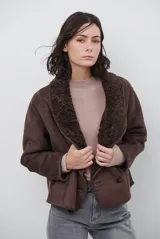 Chaqueta tipo gamulán de color marrón, con solapas amplias forradas en corderito sintético oscuro. Presenta un diseño cruzado con botones frontales y mangas largas, ideal para un estilo invernal.