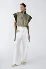 Top verde militar con cuello alto, cierre frontal con cremallera y lazos laterales.