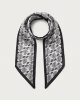 Pañuelo de seda blanco y negro con estampado paisley, bordes negros y un dije dorado en forma de espiral.