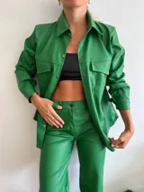 Camisa verde con textura de cocodrilo, de mangas largas y corte holgado. Presenta dos bolsillos con solapa en el pecho y cierre frontal con botones.