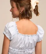 Blusa corta de tricolina a rayas celestes y blancas, con escote elástico, mangas cortas abullonadas con frufrú y fruncido en el bajo.