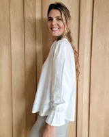 Blusa de algodón color azul, de corte suelto, con mangas largas abullonadas y cuello con volados y escote en V.