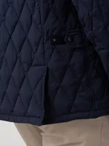 Campera acolchada azul marino con costuras en rombos, cuello de pana negro y cierre frontal con botones a presión. Incluye bolsillos laterales con ribete de pana y broches ajustables en la cintura.