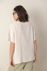 Blusa celeste de lino con escote en V, mangas cortas y detalle de bordado calado en el canesú.