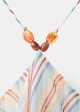 Vestido largo con diseño halter, estampado de rayas verticales en tonos celestes, naranjas y blancos, con detalle de volantes en el escote y abalorios en el cuello.