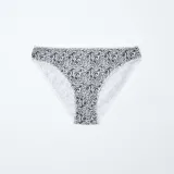 Pack de cinco braguitas de algodón, que incluye dos braguitas negras lisas, dos blancas lisas (una con estampado de lunares pequeños) y una braguita con estampado floral en blanco y negro. Todas tienen detalles de encaje en los bordes.