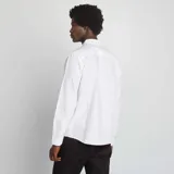 Camisa blanca de corte recto, con cuello abotonado y mangas largas.