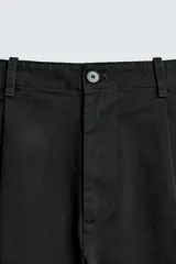 Pantalón de corte balloon fit y estilo relajado, confeccionado en tejido de algodón. Presenta pliegues frontales, cintura con trabillas, cierre frontal con cremallera y botón, bolsillos delanteros y bolsillos traseros de vivo.