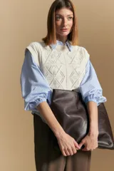 Chaleco tejido color crema con diseño de rombos calados, cuello redondo y sisas.