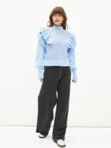 Buzo de tejido de punto calado en color lila, con cuello alto, mangas largas con puños ajustados y detalle de volados en los hombros.